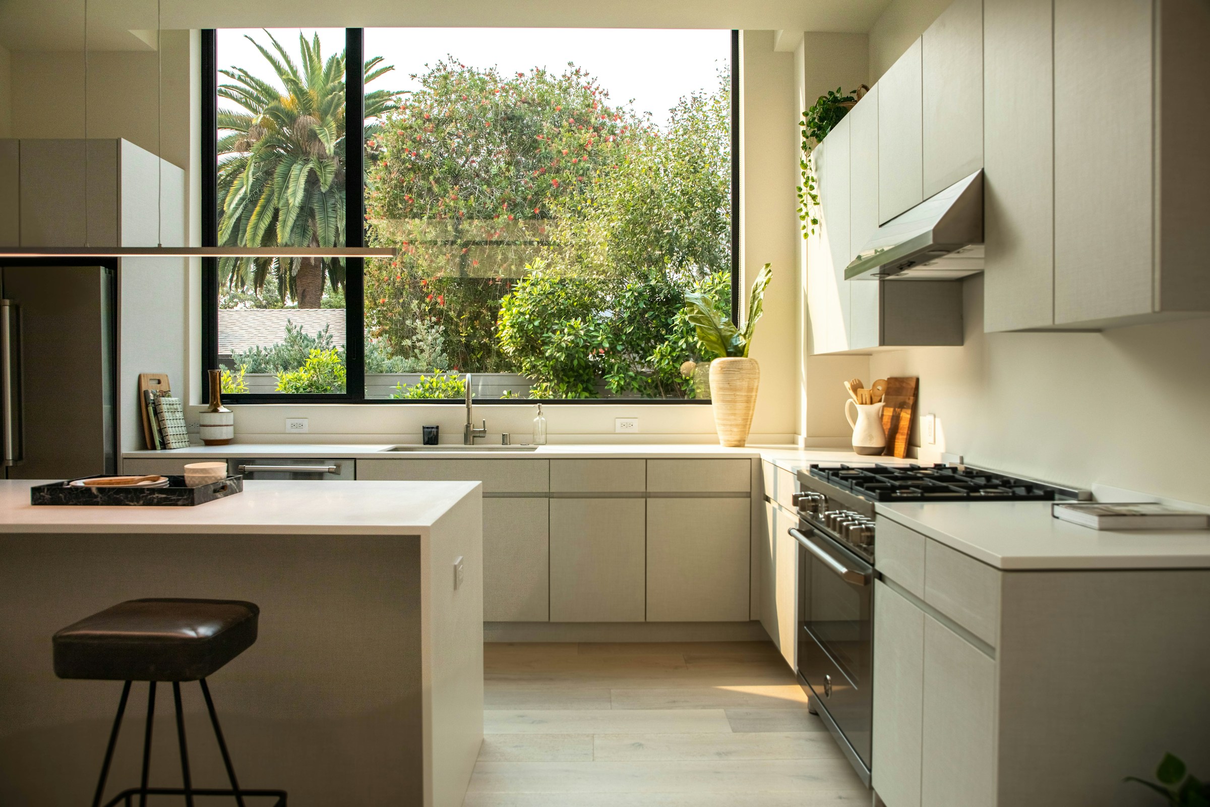 Sunlit modern kitchen with a white island and floor-to-ceiling windows